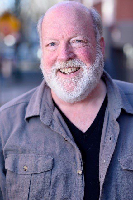 A bald man with a beard and mustache is smiling for the camera.