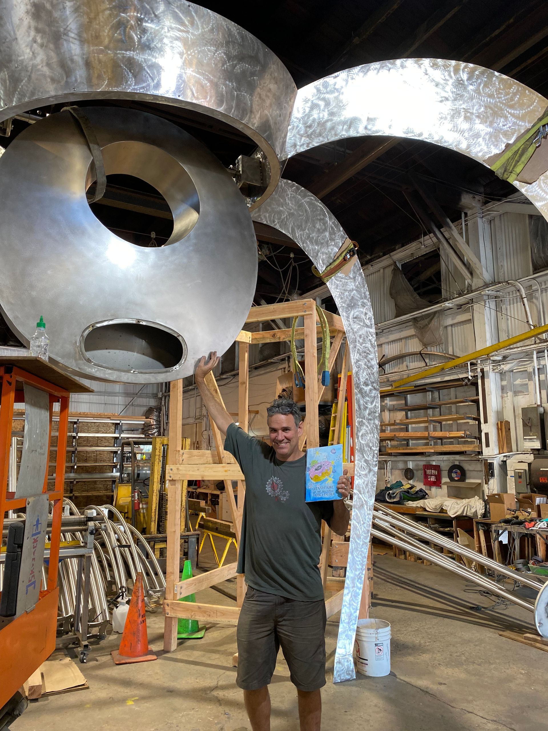 A man is standing in front of a large metal sculpture.