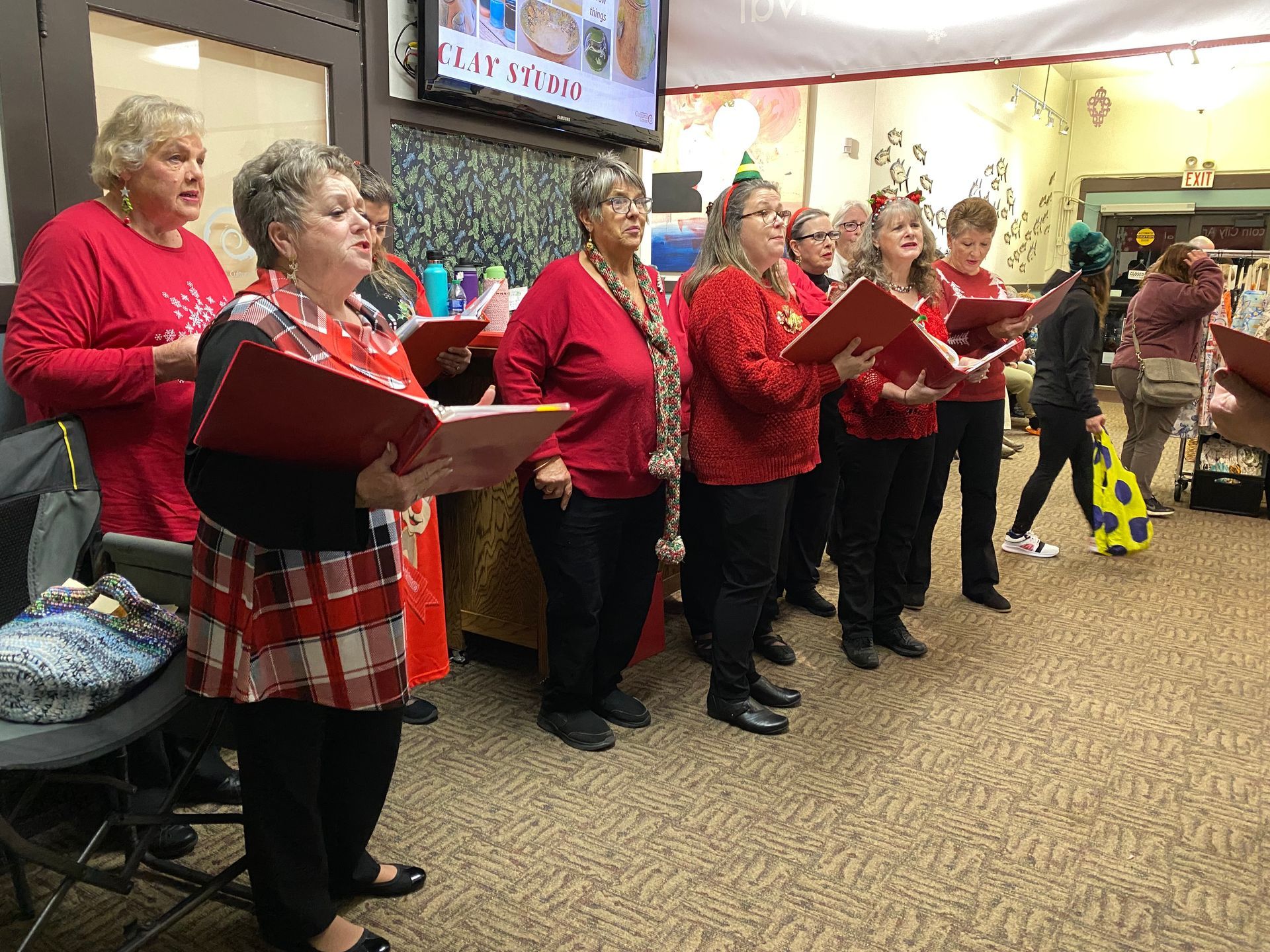 A group of women are singing christmas carols in a room.