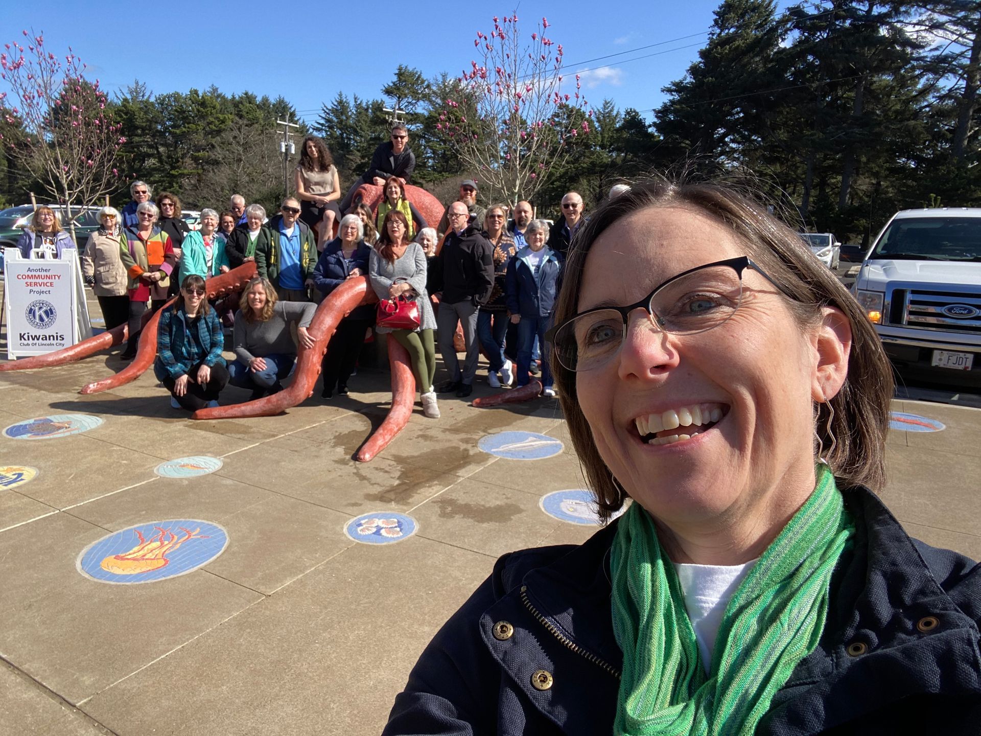 A woman is taking a selfie in front of a group of people.