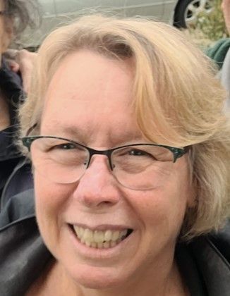 A close up of a woman wearing glasses and smiling.