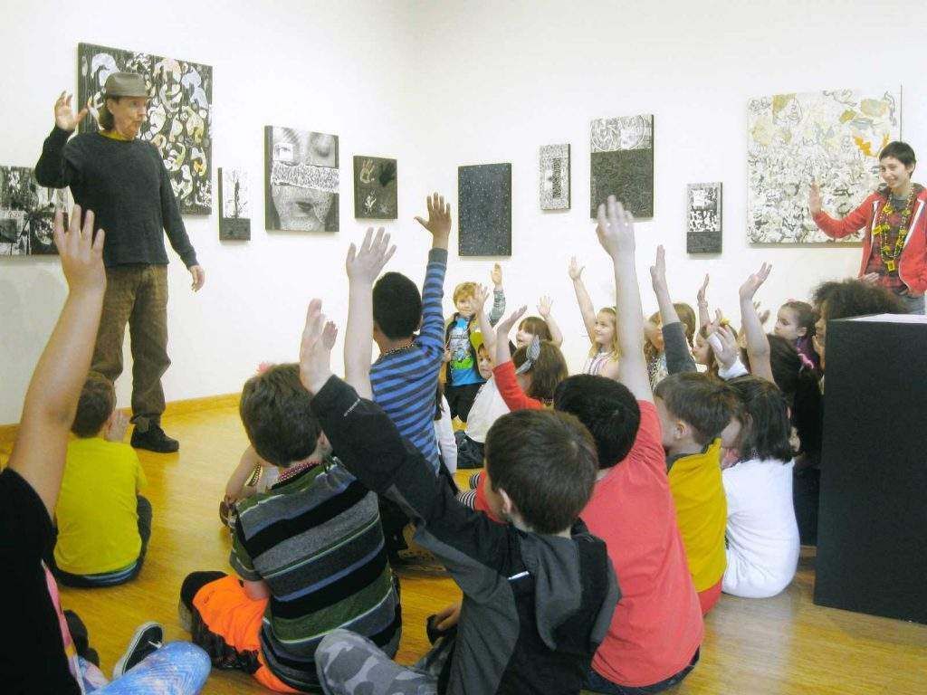 A group of children are raising their hands in a museum