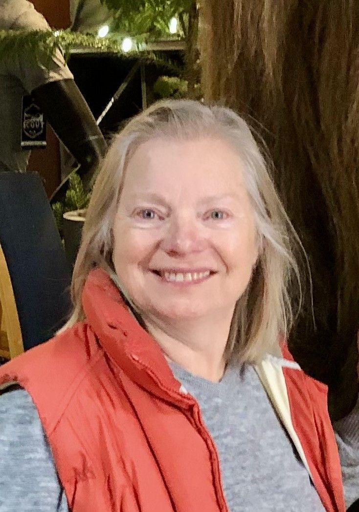 A woman wearing an orange vest is smiling for the camera
