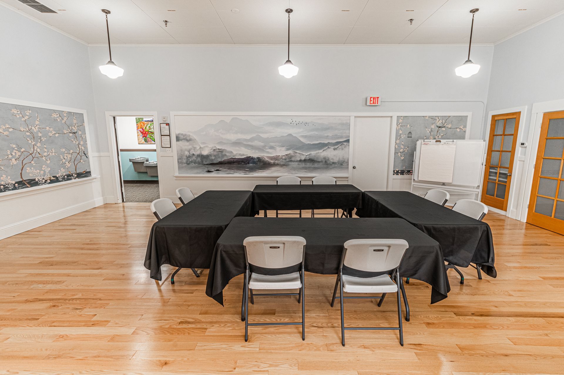 A large room with tables and chairs and a painting on the wall.