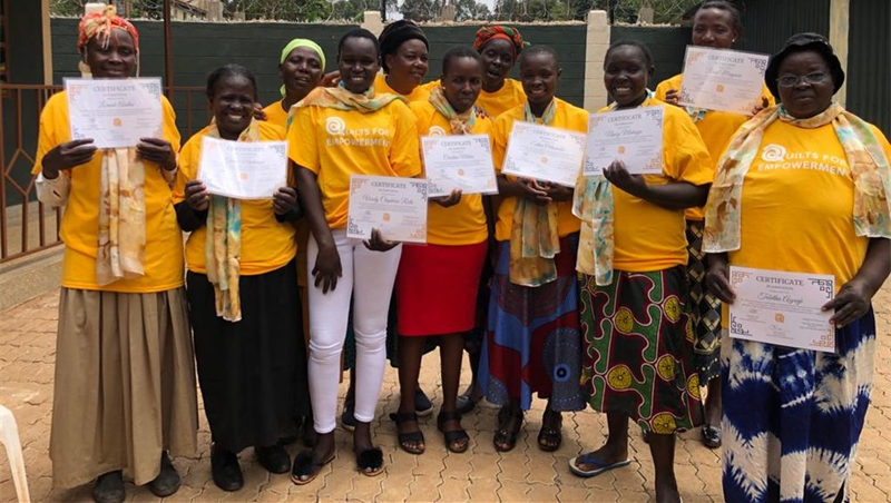 A group of women in yellow shirts are standing next to each other holding certificates.
