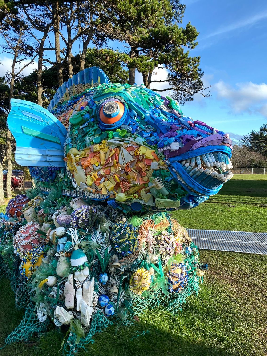 A statue of a fish made out of plastic bottles and fishing nets.
