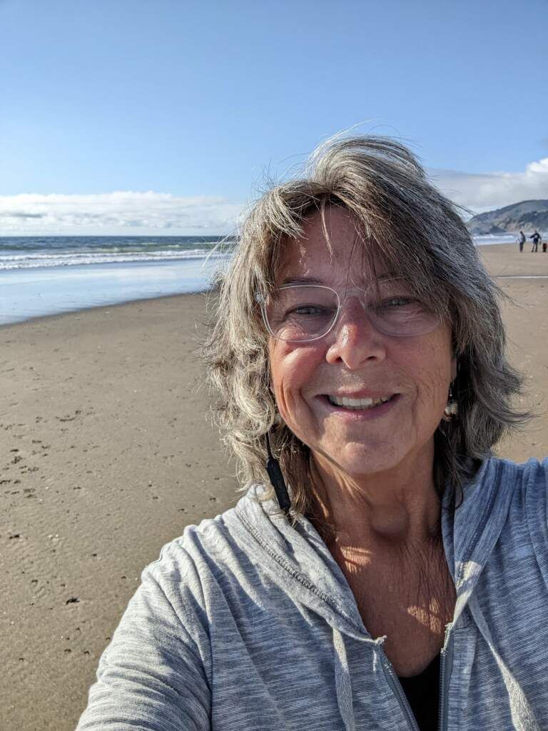 A woman is taking a selfie on the beach.