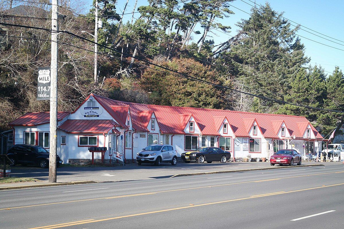 A row of motels with red roofs are lined up on the side of the road.