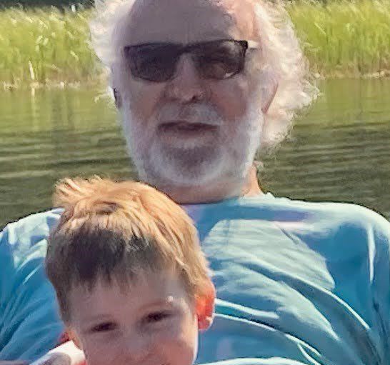 A man is holding a little boy in his arms while sitting on a boat.