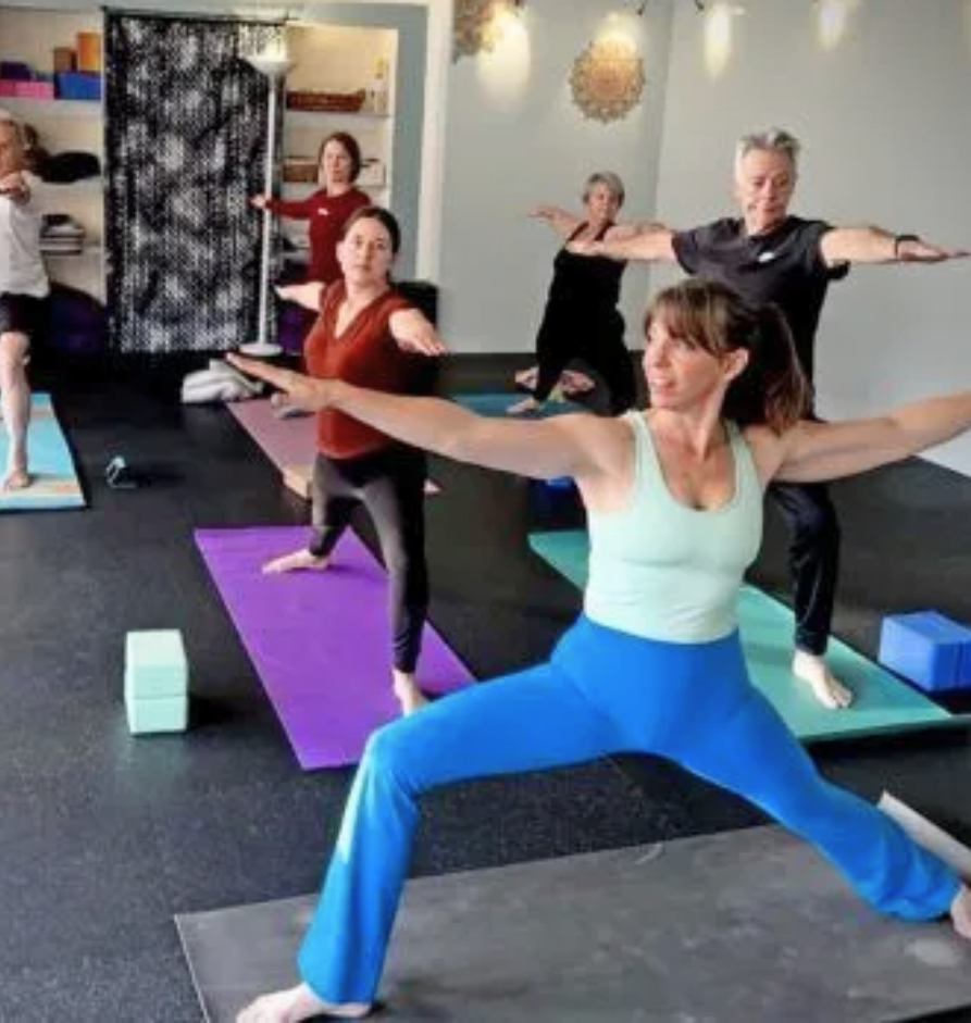 A woman with white hair is sitting at a table smiling.