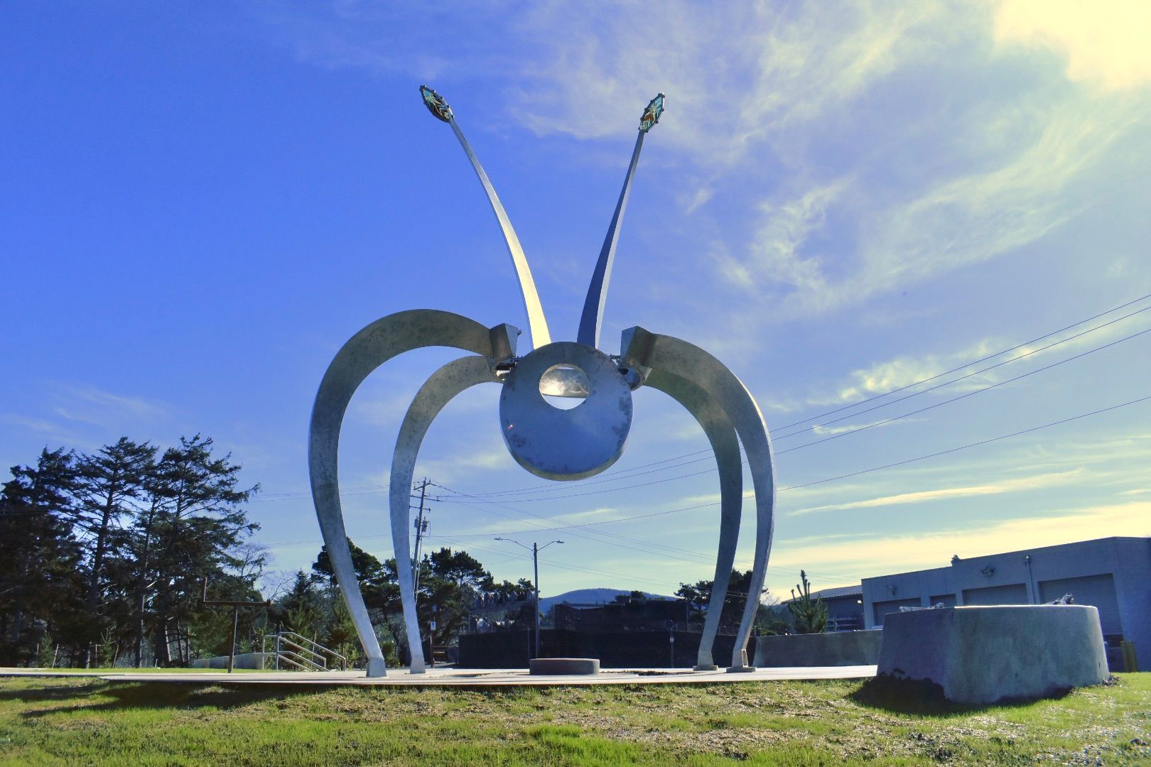 A large metal sculpture of a bug with a blue sky in the background