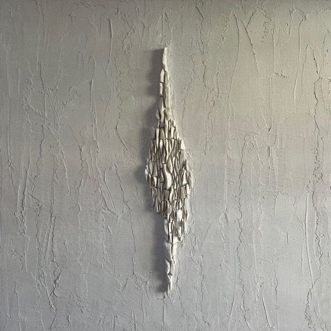 A white sculpture is hanging on a white wall.