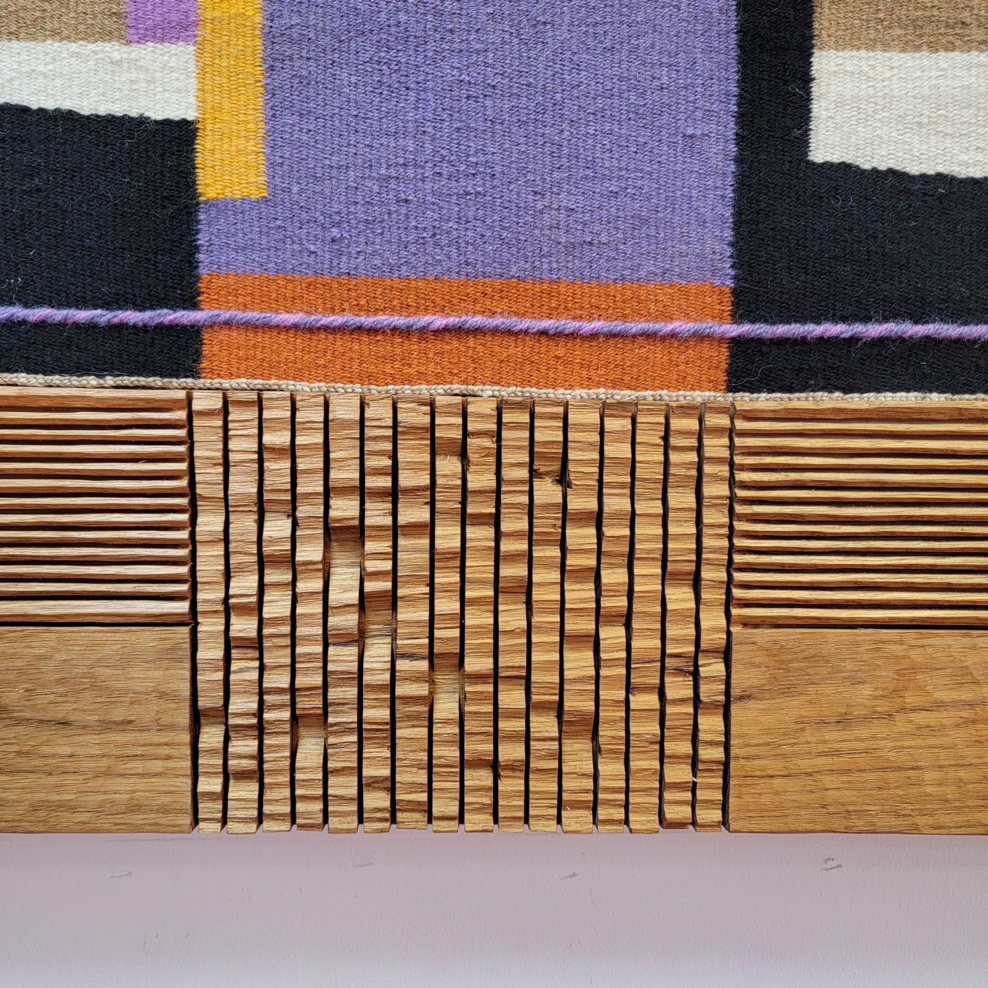 A close up of a wooden frame with a colorful rug on it.