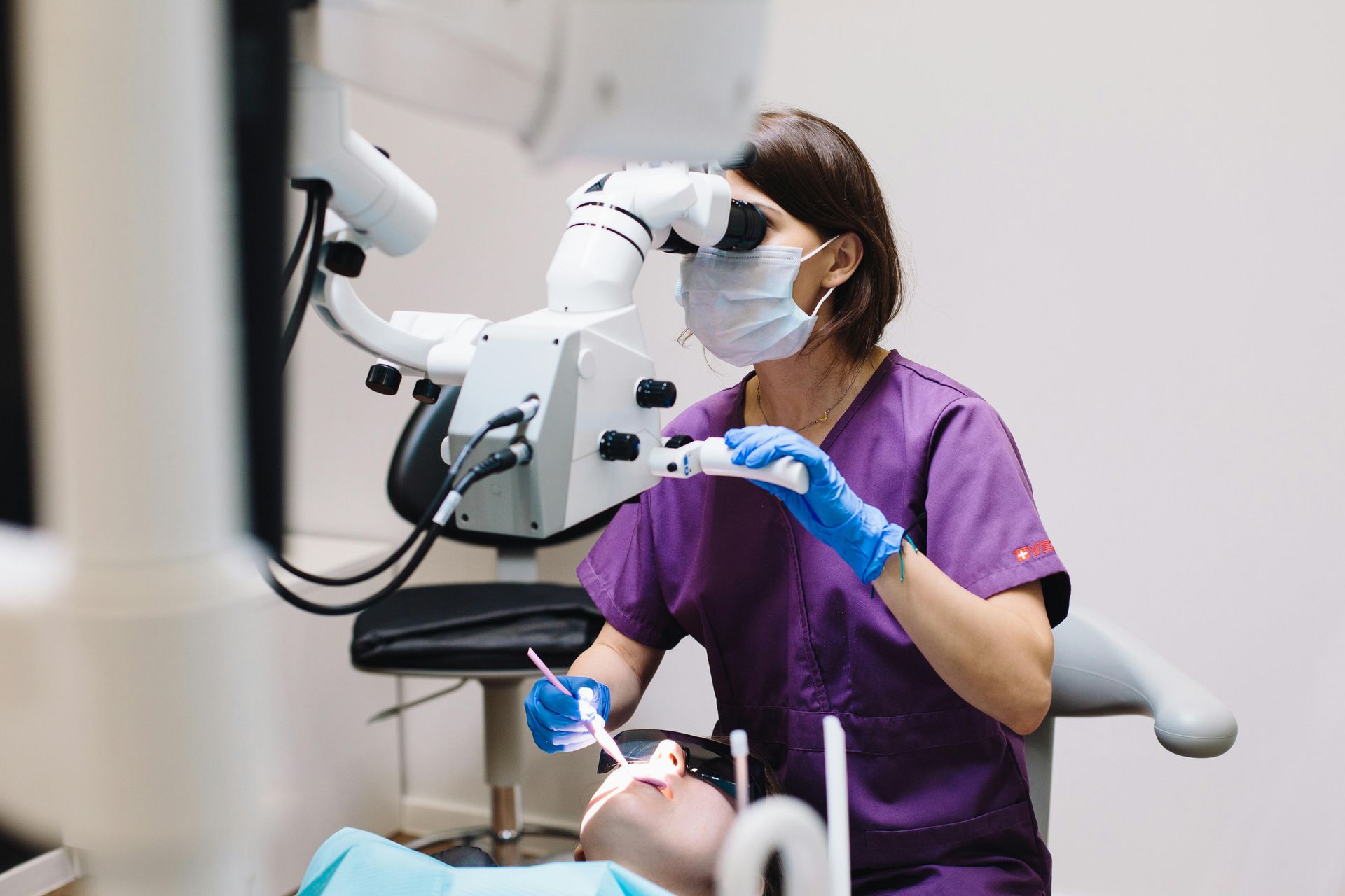 A dentist is examining a patient 's teeth under a microscope.