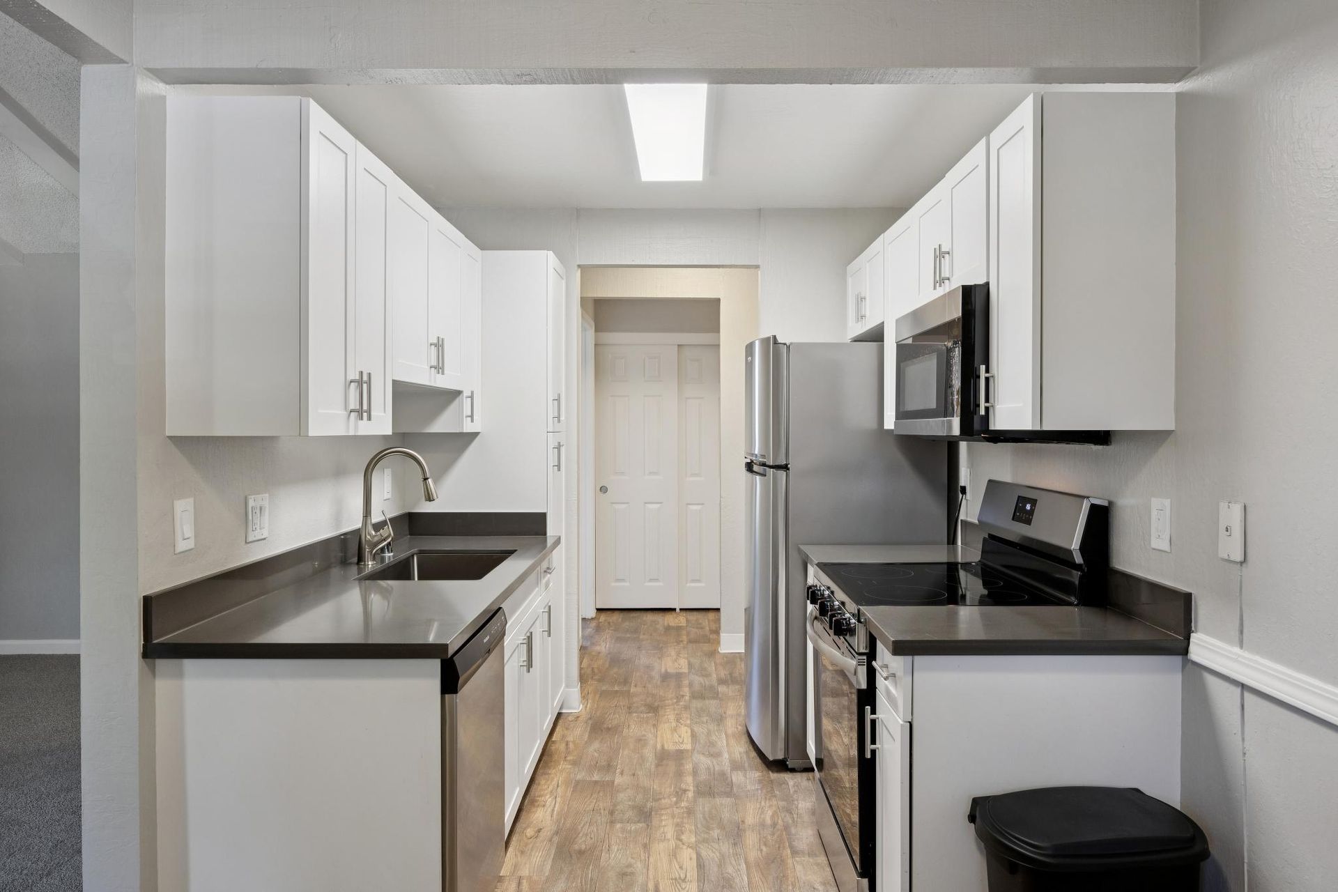 Kitchen with white cabinets, stainless steel appliances, and dark countertops.