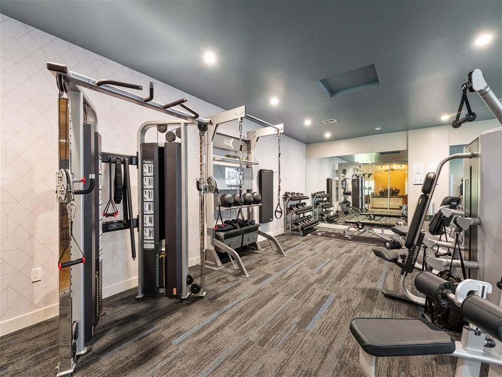 Indoor community gym with weight machines, free weights, and mirrors.