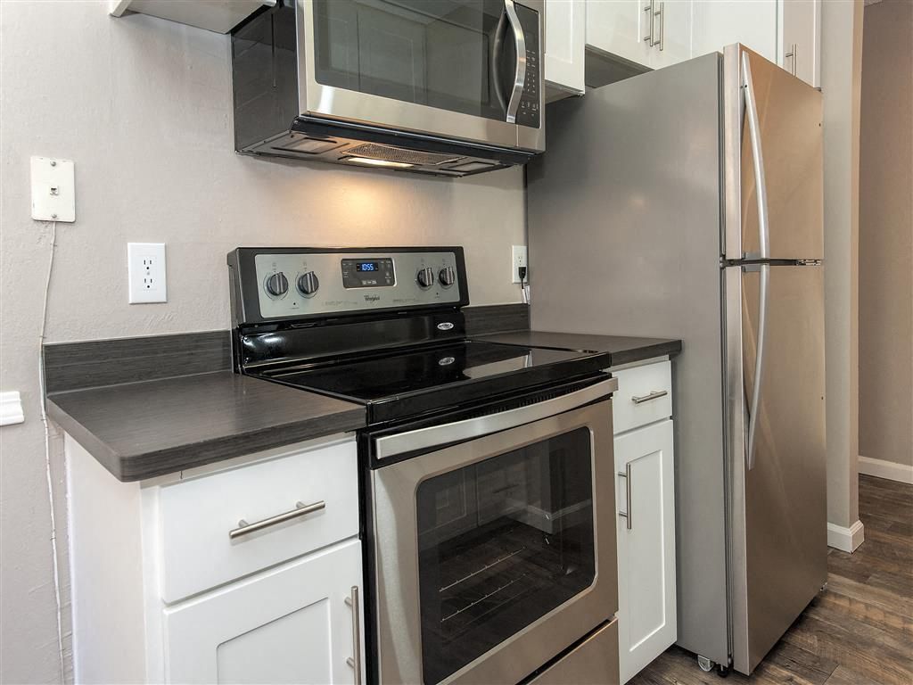 Kitchen area with stainless steel stove, microwave, and side-by-side refrigerator.