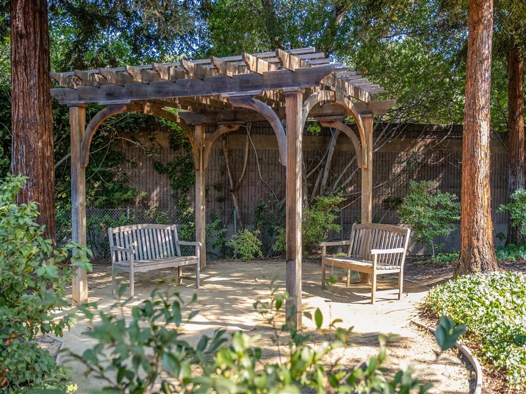 Wooden pergola with benches in a garden courtyard.