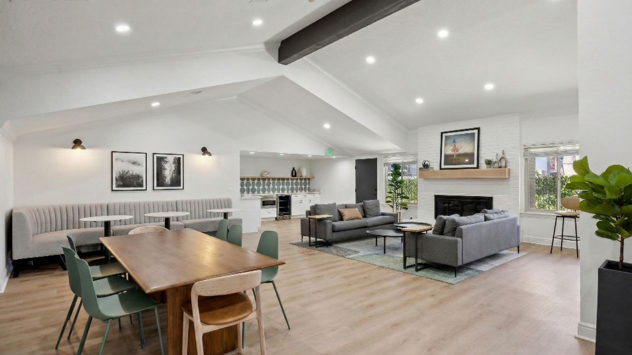 Bright, modern interior with seating areas: dining table, sofas by fireplace, and a built-in bench.