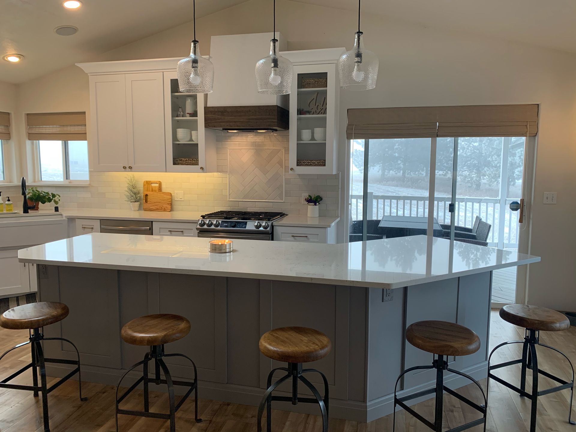 Modern kitchen with white cabinets, gray island, and industrial-style bar stools.