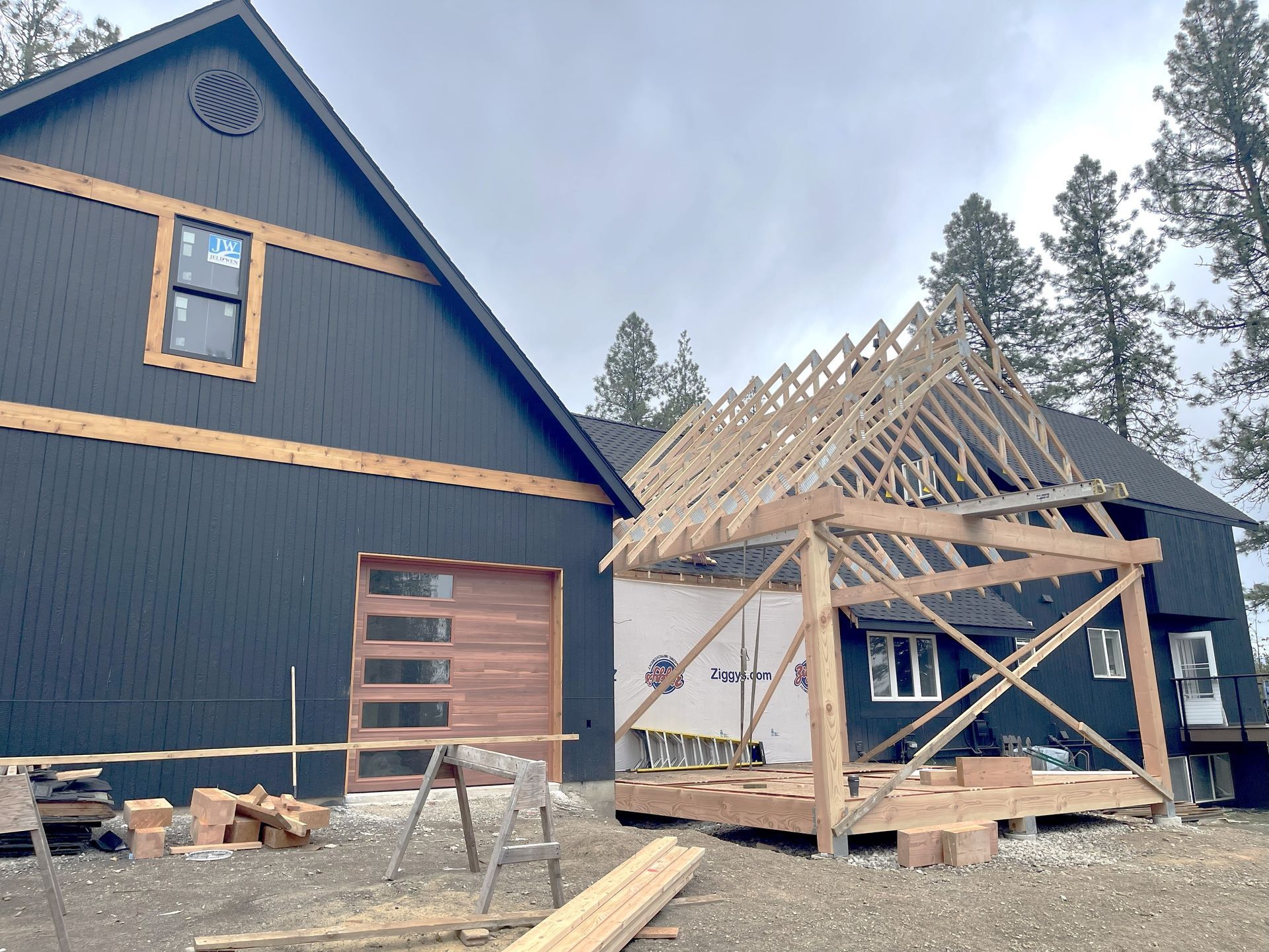 Construction of a black house with wood trim. A partially built wooden porch is attached.