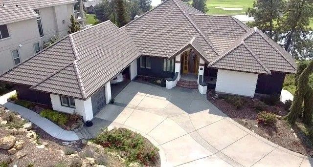 House with brown tile roof and a long driveway.