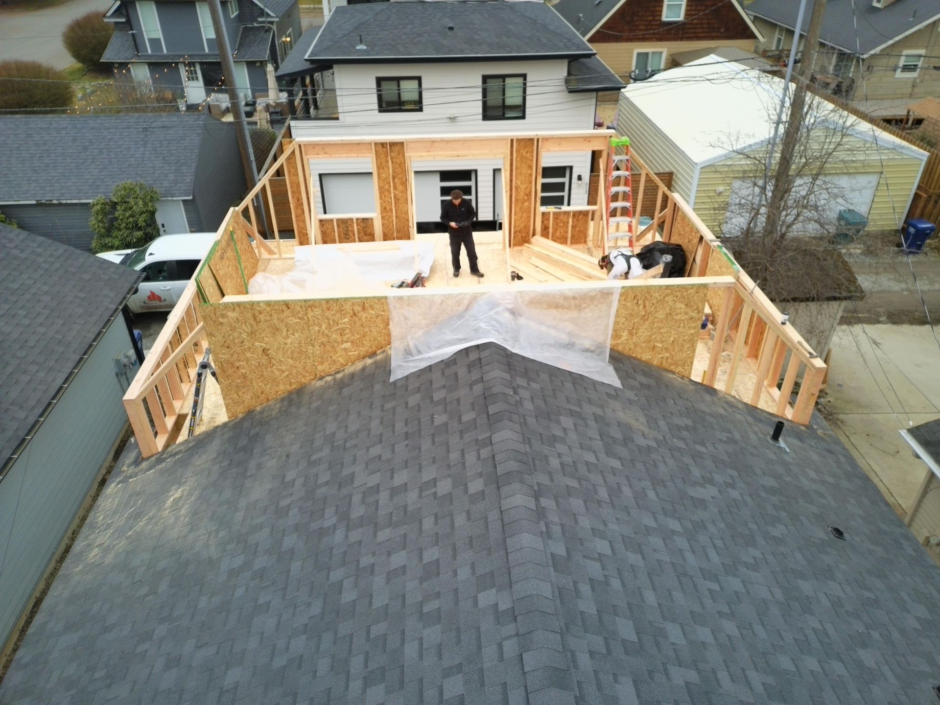 Aerial view of a house under construction with a person and a dog standing on the structure.