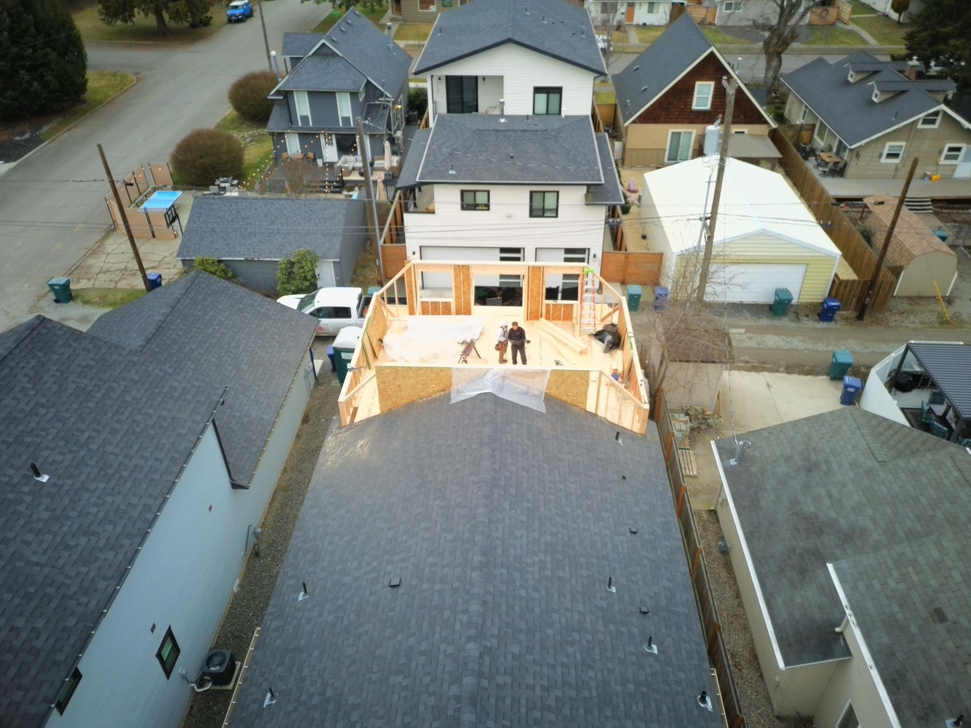 Aerial view of a house under construction; workers on a partially built deck.