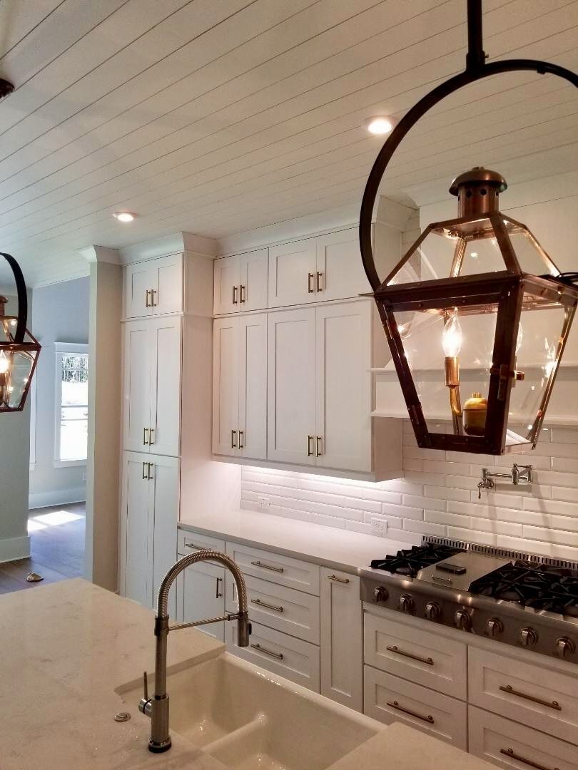 White kitchen with a large island and pendant lights.
