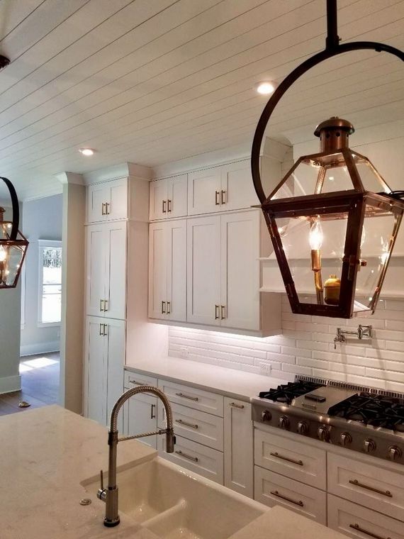 White kitchen with a large island and pendant lights.