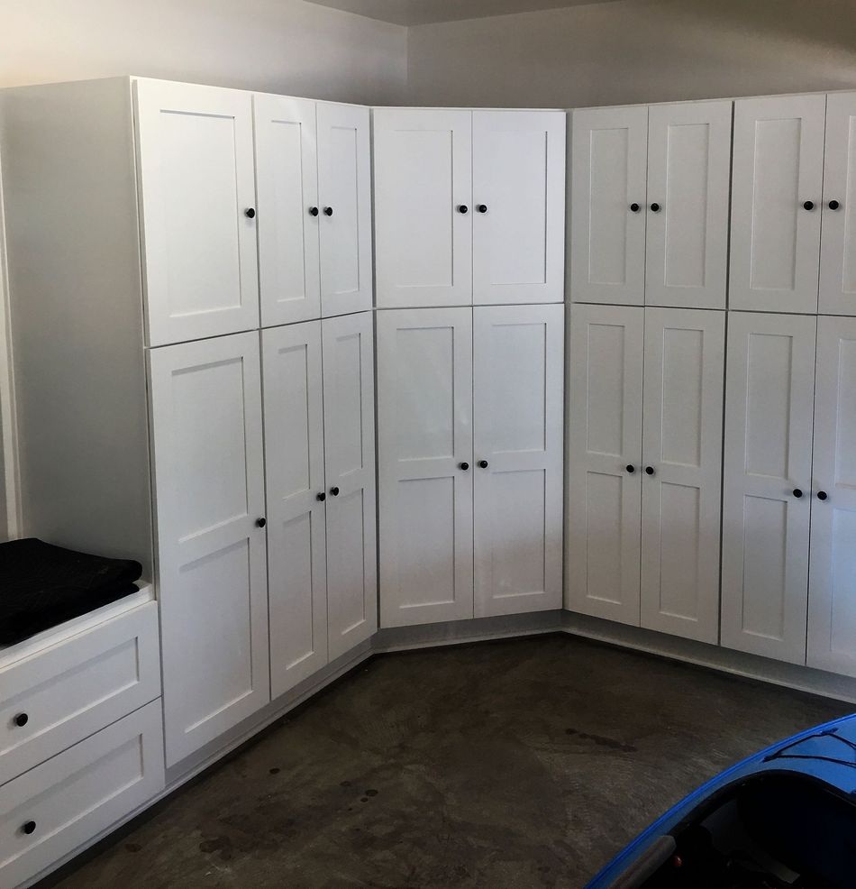 White storage cabinets in a garage, with black door knobs.