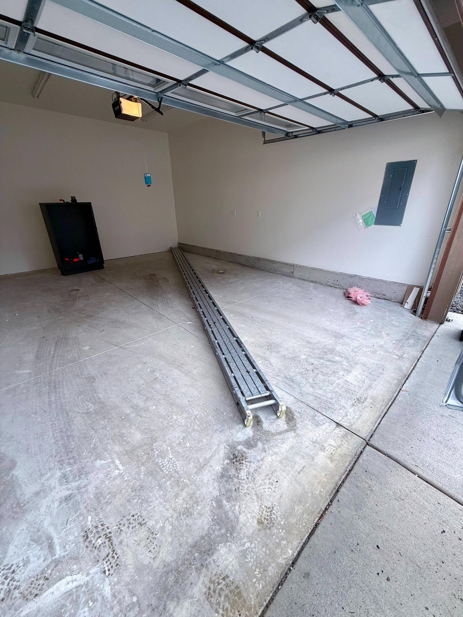 An empty garage interior with a floor drain. Light-colored walls and concrete floor.
