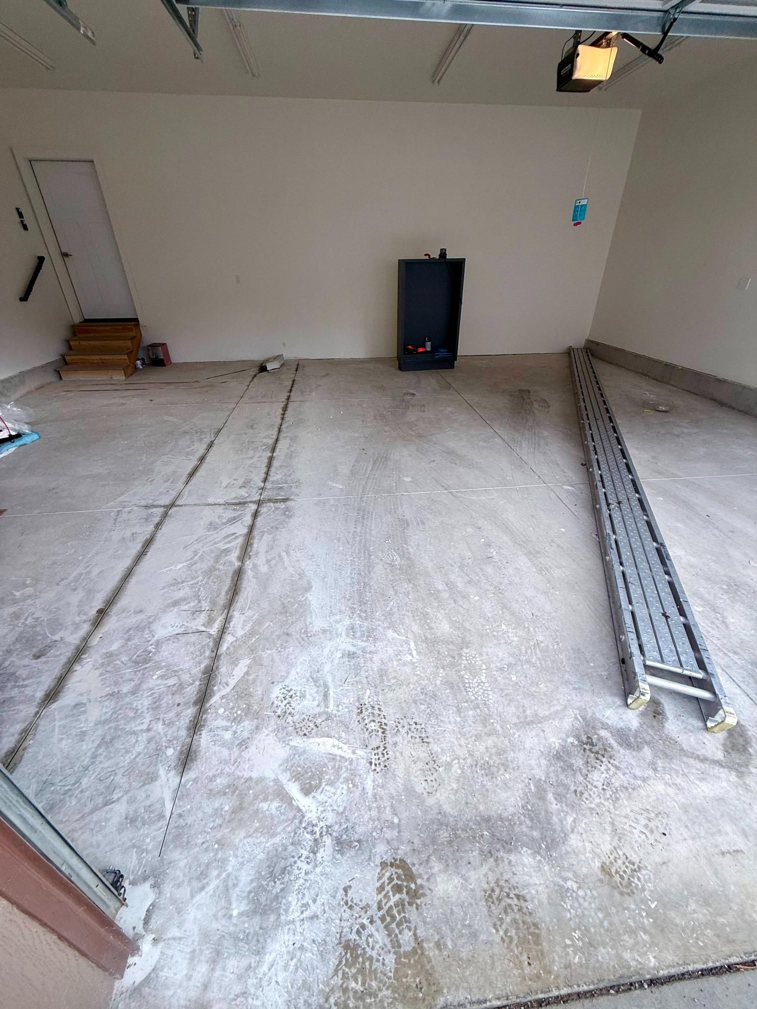Empty garage with concrete floor, door on the left, and a metal cabinet against the back wall.