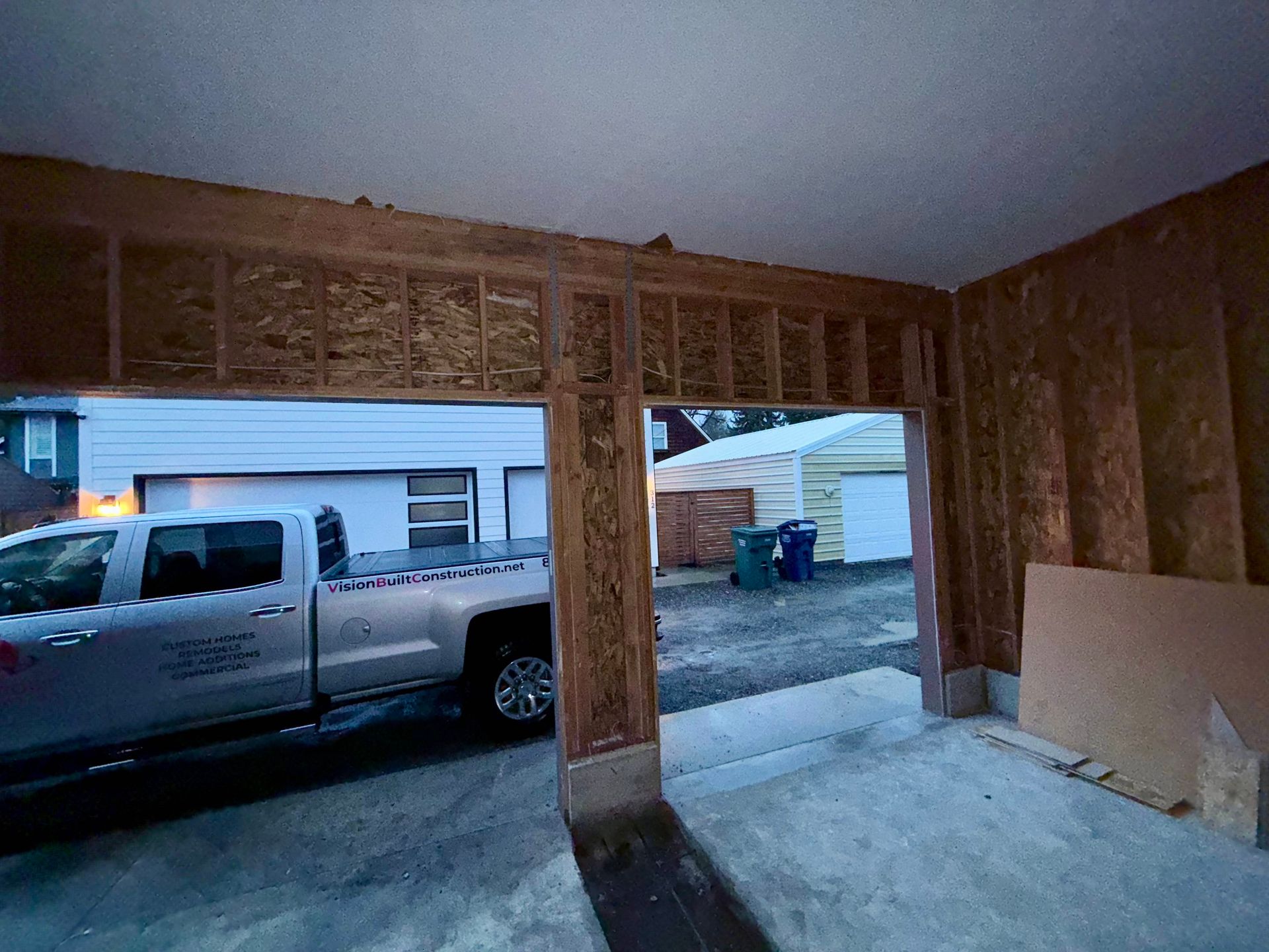 Garage under construction; open doorway with a truck visible outside, framing is exposed wood.