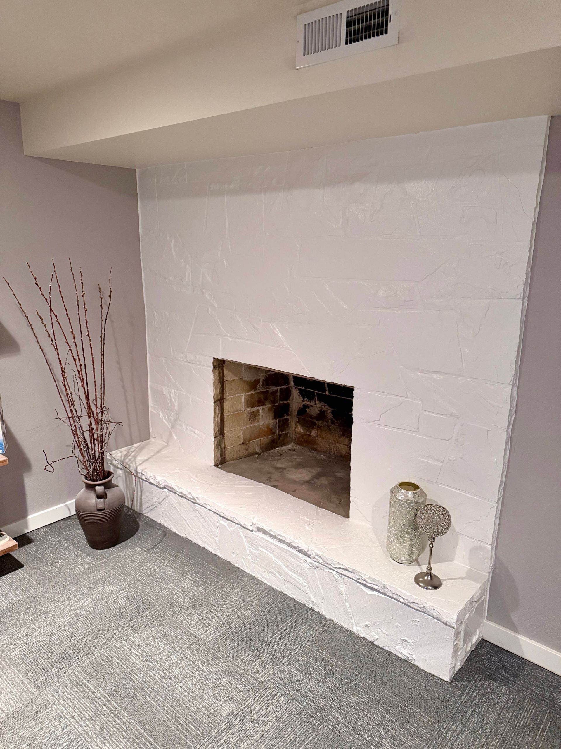 Finished basement with stairs, glass railing, white trim, light gray walls, and light wood floors.