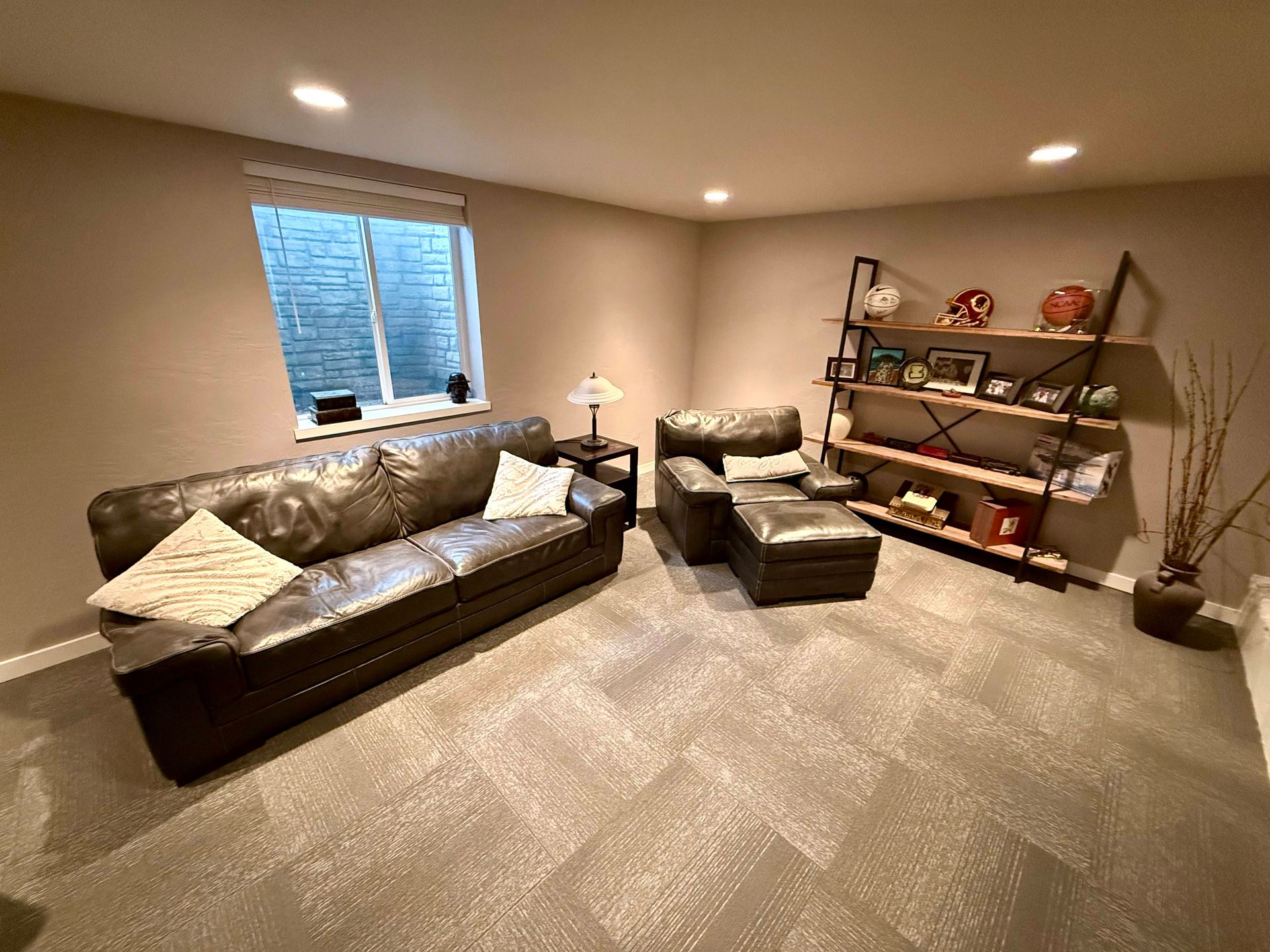 Living room with dark leather sofa and chair, bookshelves, and window.