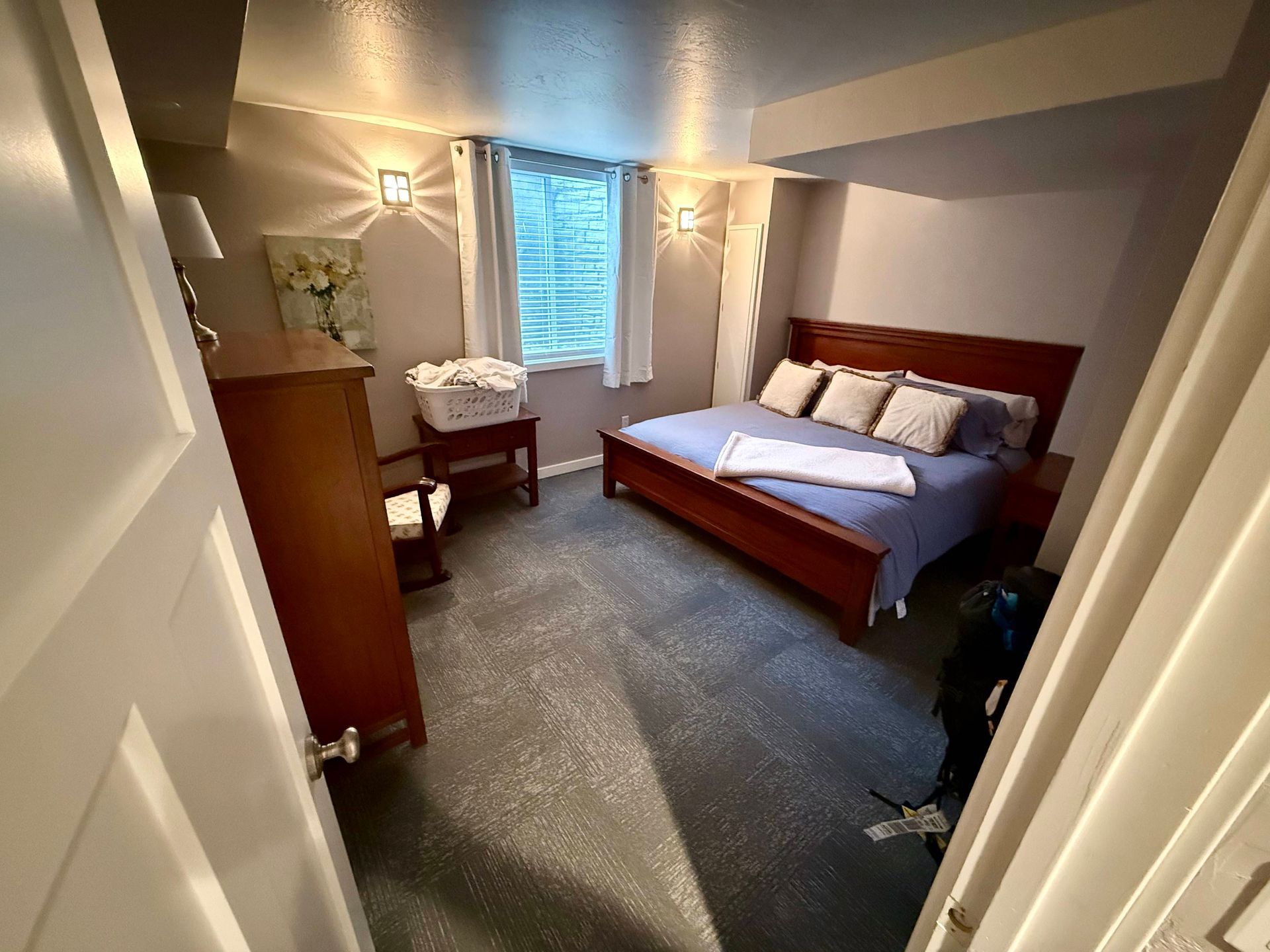 Bedroom with wooden furniture, bed, and window; gray walls, carpet, and neutral lighting.