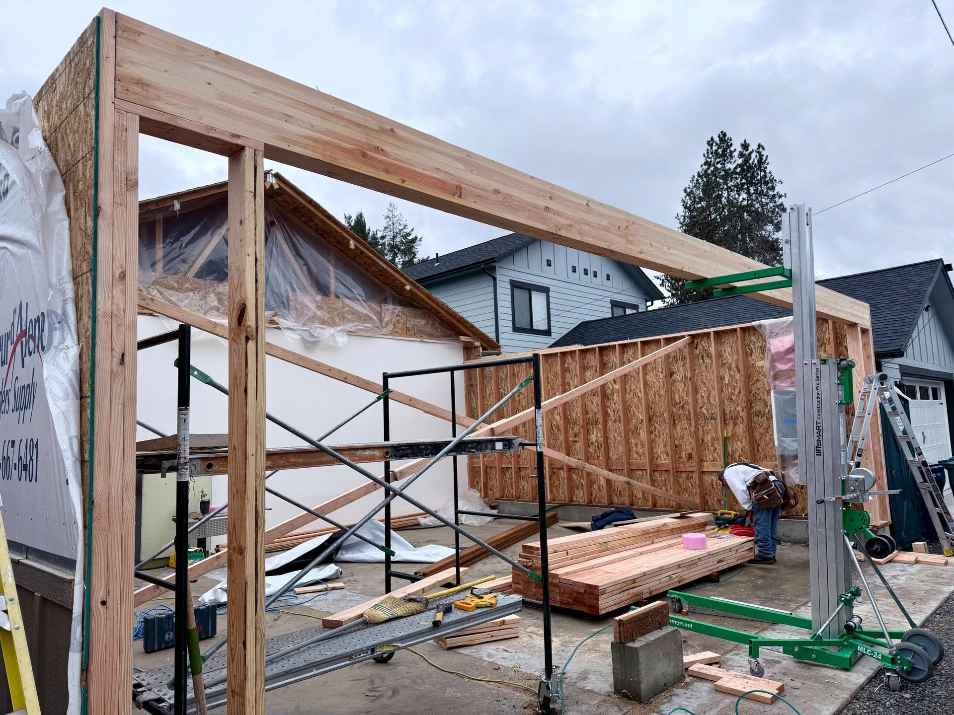 Construction site: wooden structure framing with worker and lift in progress.