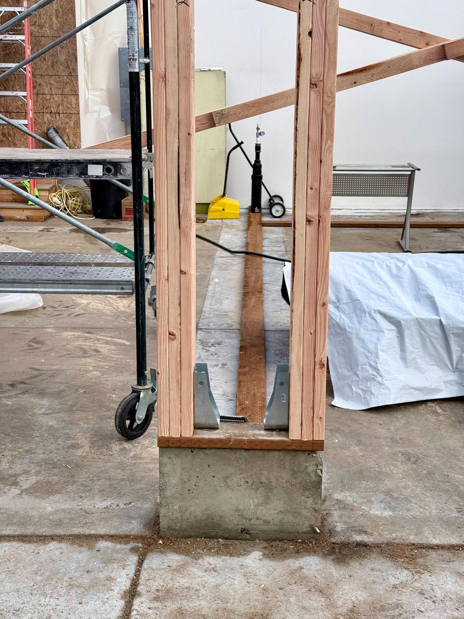 Wooden framing on a concrete base with metal supports, construction site.