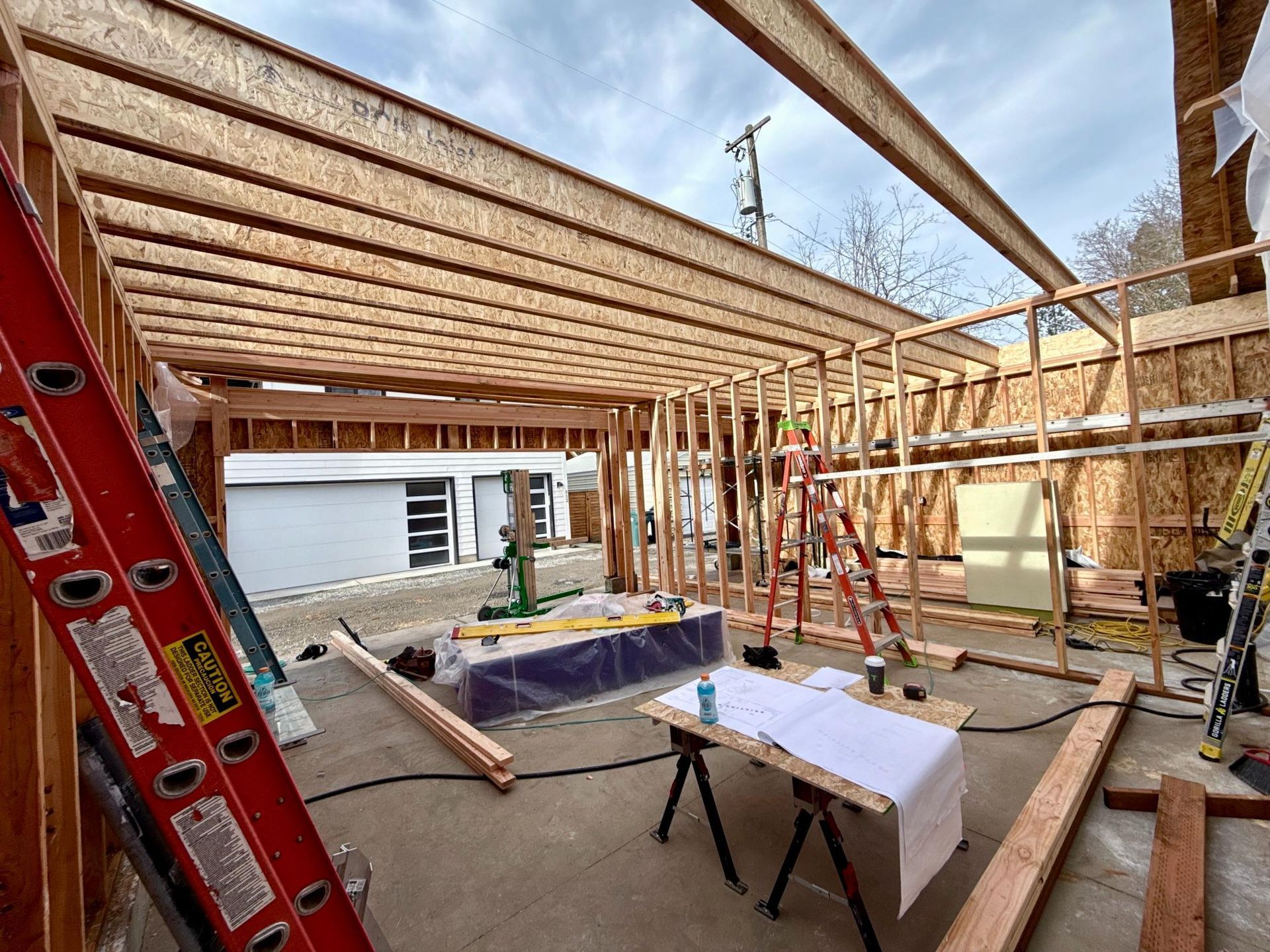 Construction site with wooden framing, lumber, and a partially built structure.