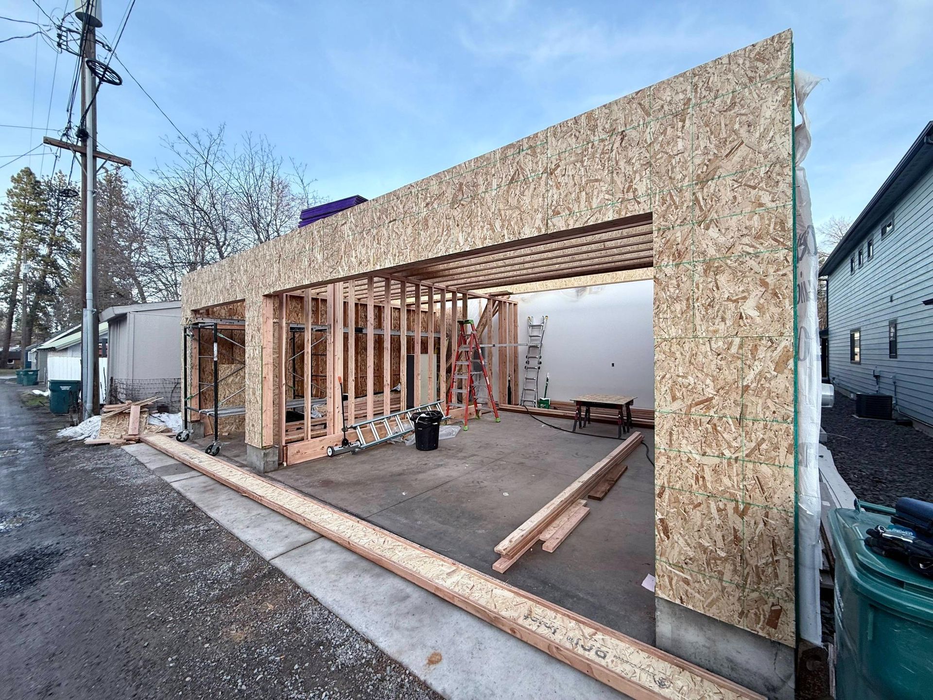 Garage construction: Wood frame with OSB sheathing. Interior framing visible. Concrete floor. Outdoors.