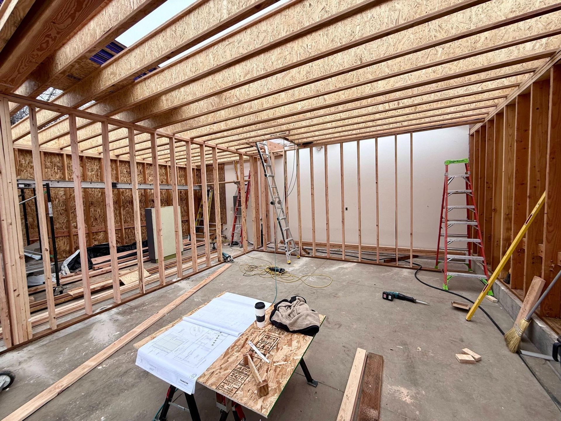 Interior view of a garage under construction with wooden framing for walls and ceiling.