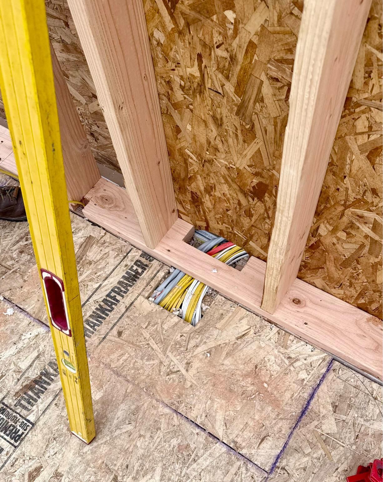 Yellow level next to a wood frame with exposed electrical wires.