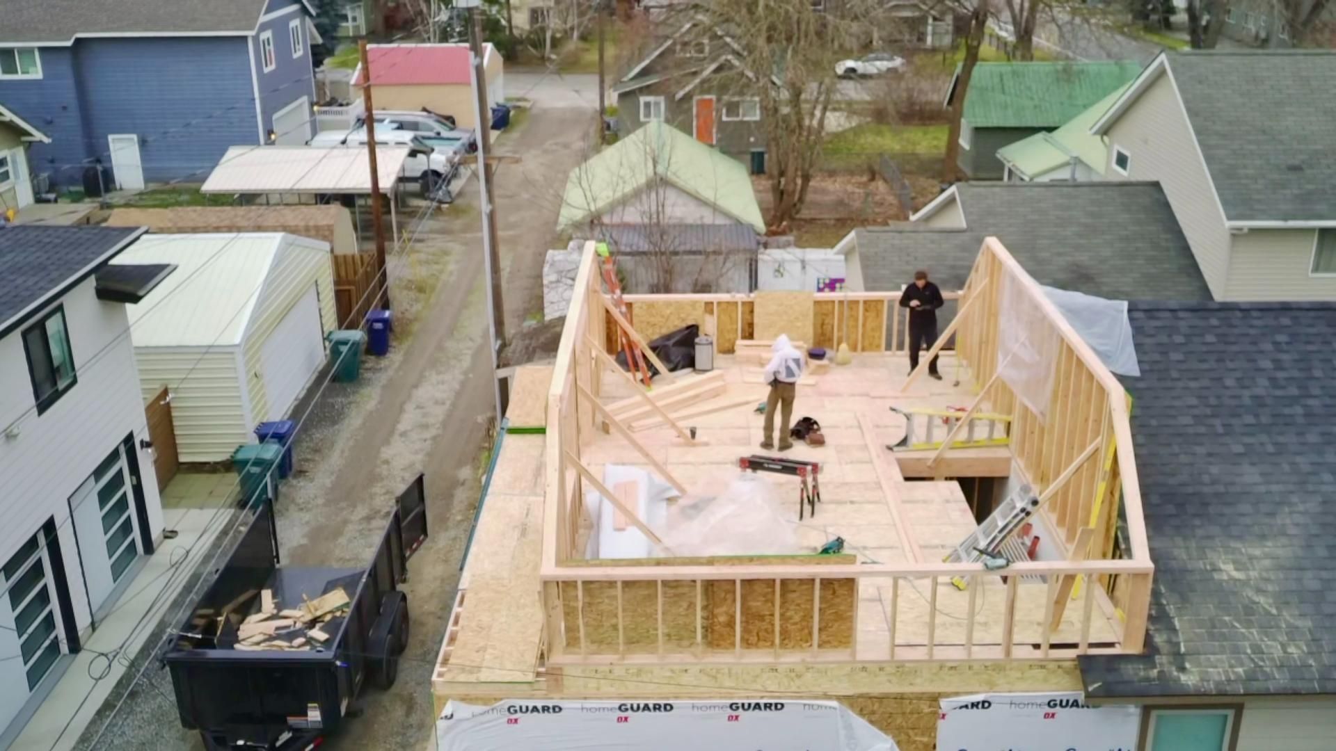 Construction of a roof addition on a house; workers on the wooden frame.