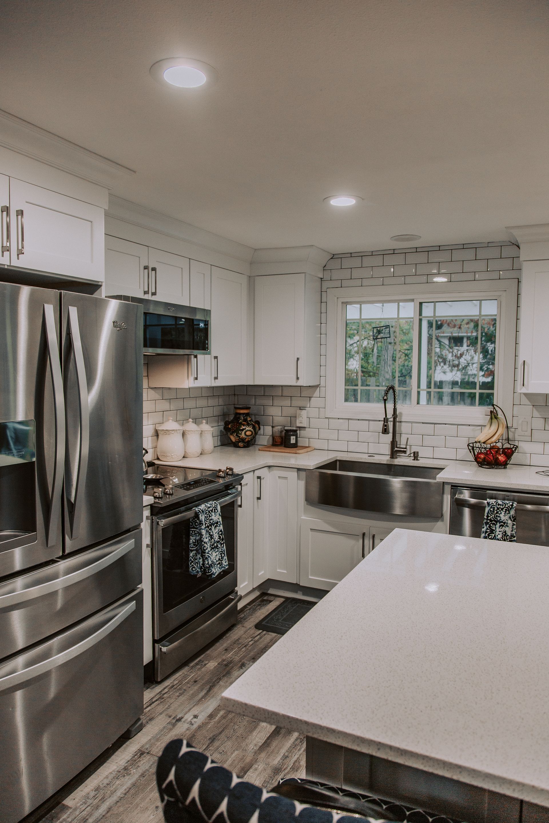 Modern white kitchen with stainless steel appliances, sink, and countertop island.