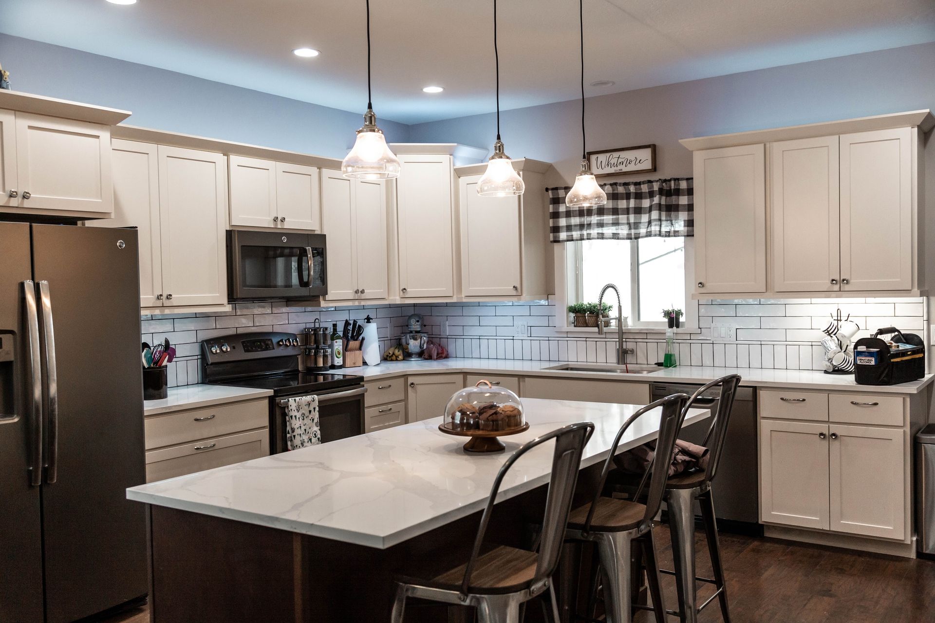 Cream-colored kitchen with an island, bar stools, and a marble countertop.