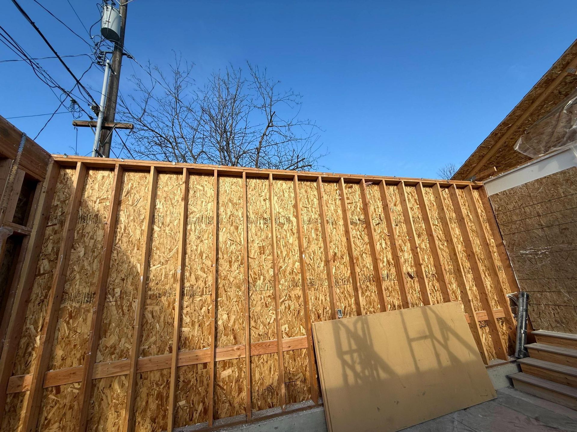 Framed wooden wall under construction against a clear blue sky.