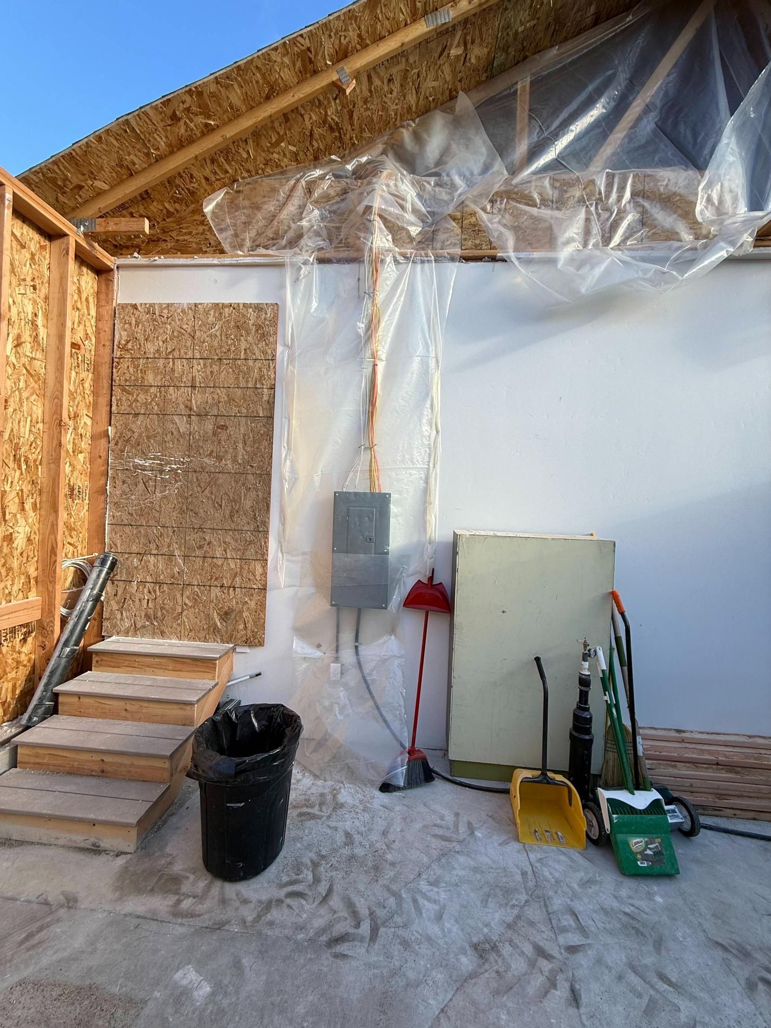 Interior of a garage under construction; unfinished walls, stairs, and electrical box.