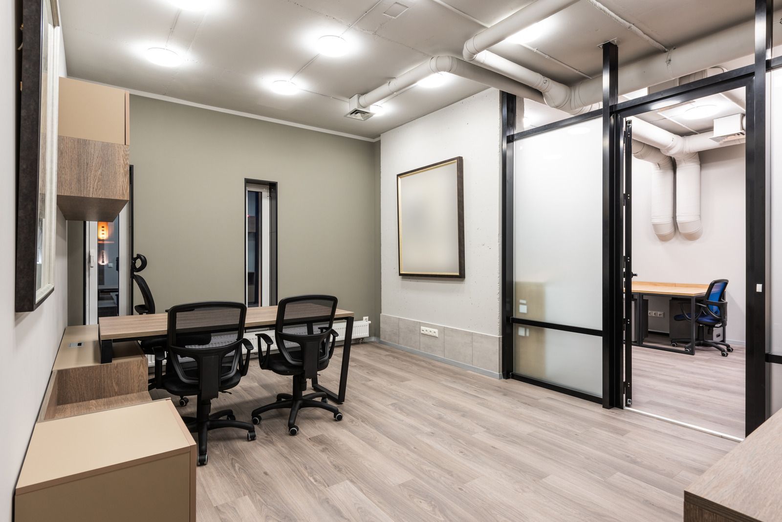 Office space with light wood floors, conference table, and glass-walled room.