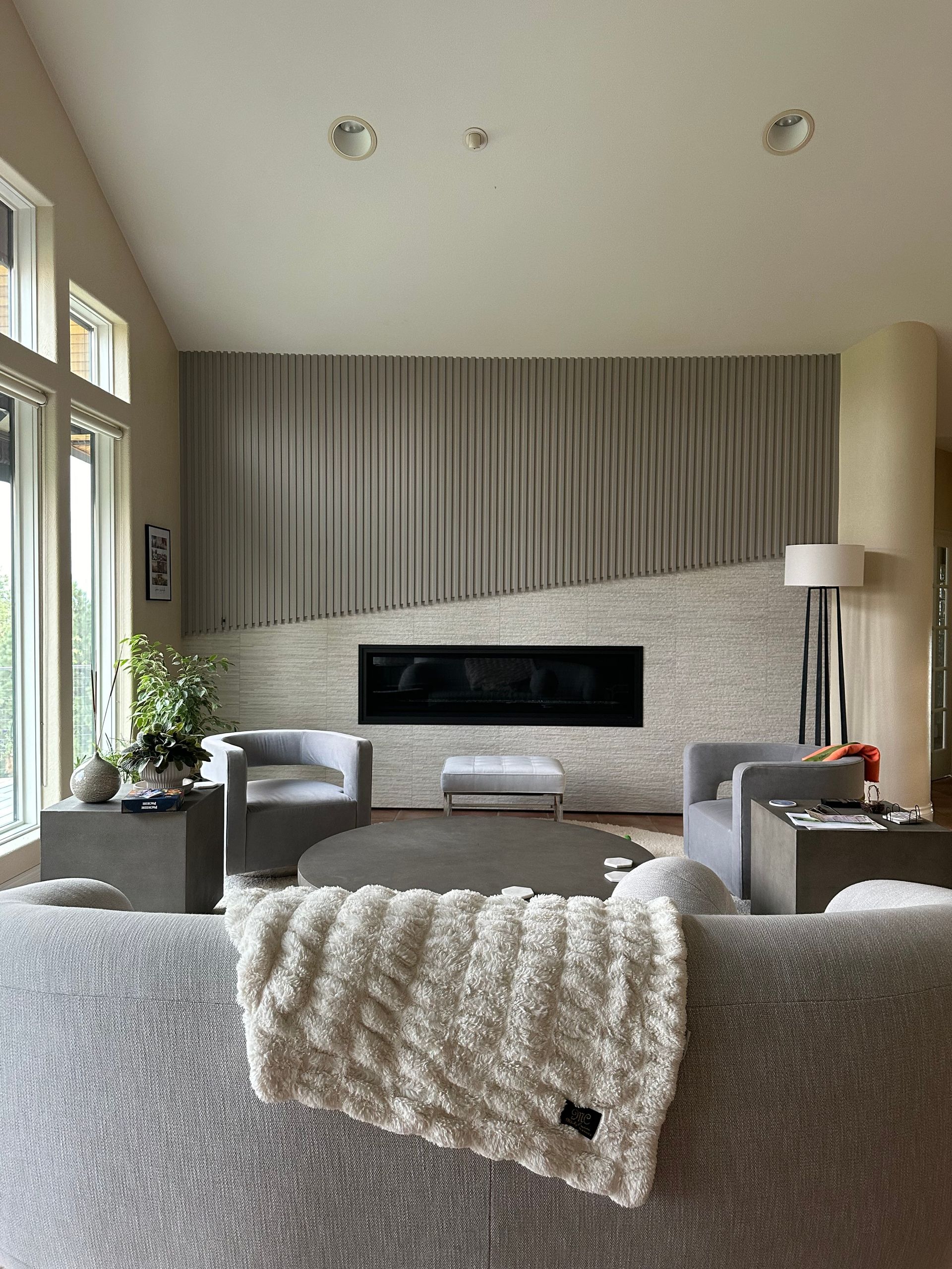 Living room with modern fireplace and decor, gray tones, and a textured wall.